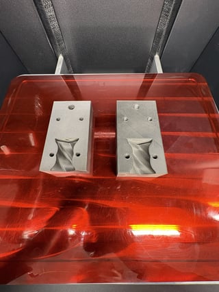 Two metal molds with spiral cone designs in a red plastic storage container with gray handles