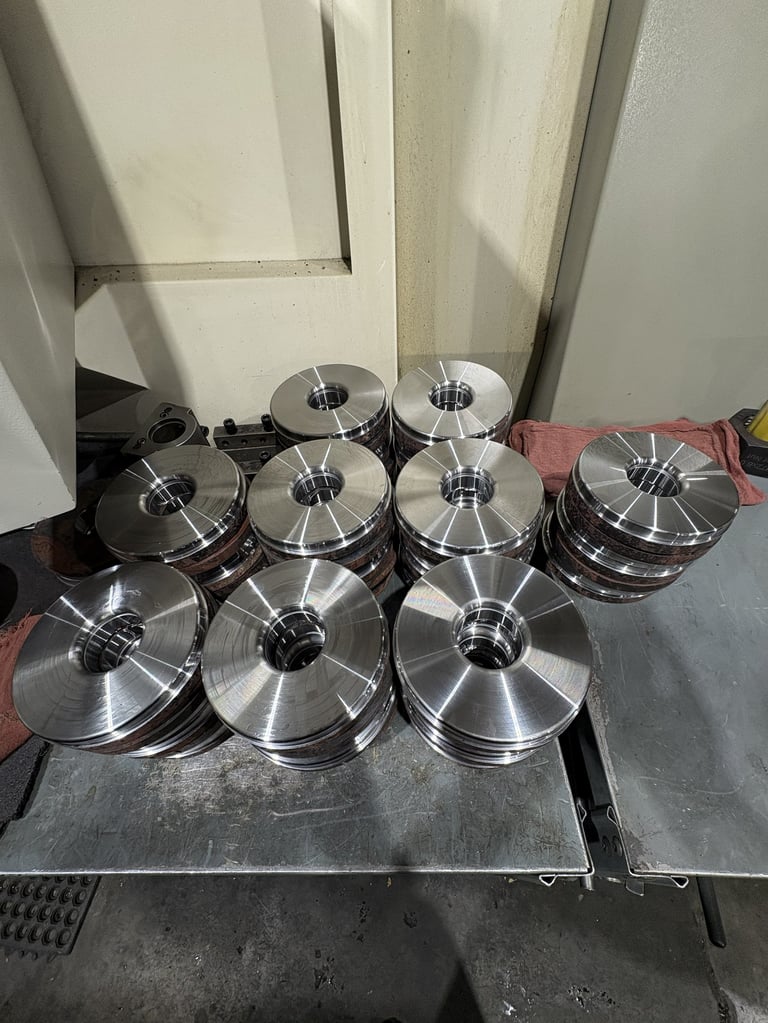 Multiple metallic wire spools stacked on a table in an industrial setting